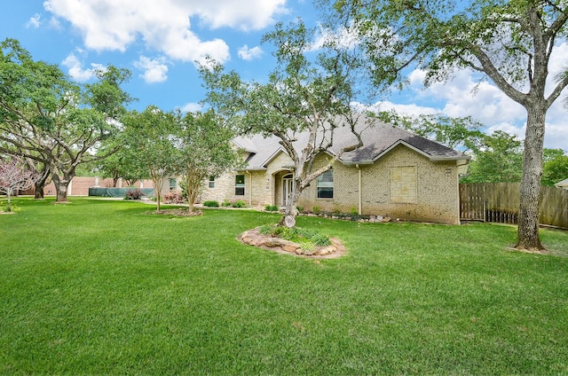 view of front of house featuring brick siding, a shingled roof, a front lawn, and fence