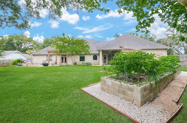 back of property with a garden, a lawn, and fence