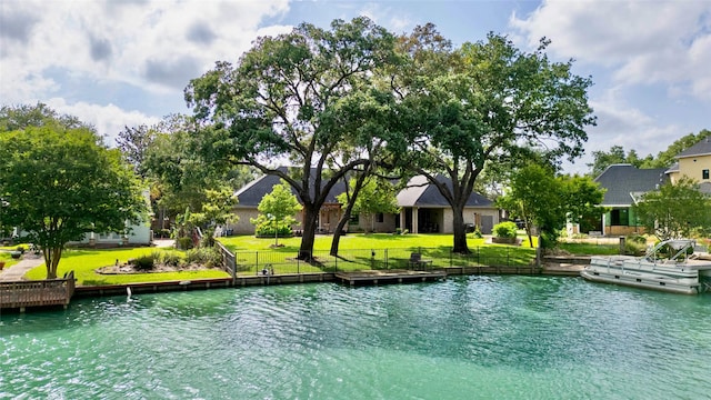 view of swimming pool featuring a yard, a water view, and a boat dock