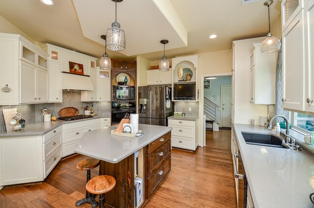 kitchen with a kitchen island, sink, white cabinets, hanging light fixtures, and black appliances