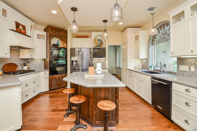 kitchen with pendant lighting, sink, a breakfast bar area, a center island, and black appliances