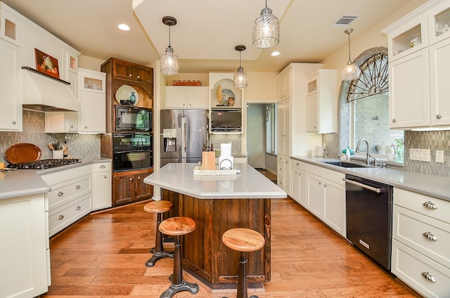 kitchen with visible vents, a sink, black appliances, light countertops, and light wood-type flooring