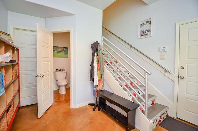 stairway featuring baseboards and finished concrete floors