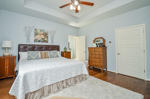 bedroom with dark wood finished floors, ceiling fan, baseboards, and a tray ceiling