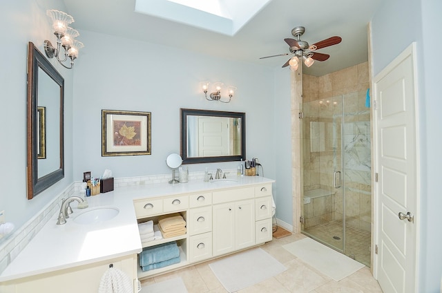 bathroom with a ceiling fan, double vanity, a skylight, a stall shower, and a sink