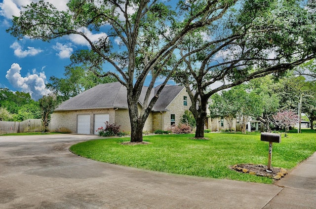 view of front of house with concrete driveway, fence, a garage, and a front yard