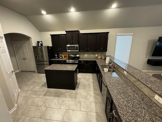 kitchen with light tile patterned flooring, stainless steel appliances, stone counters, decorative backsplash, and vaulted ceiling