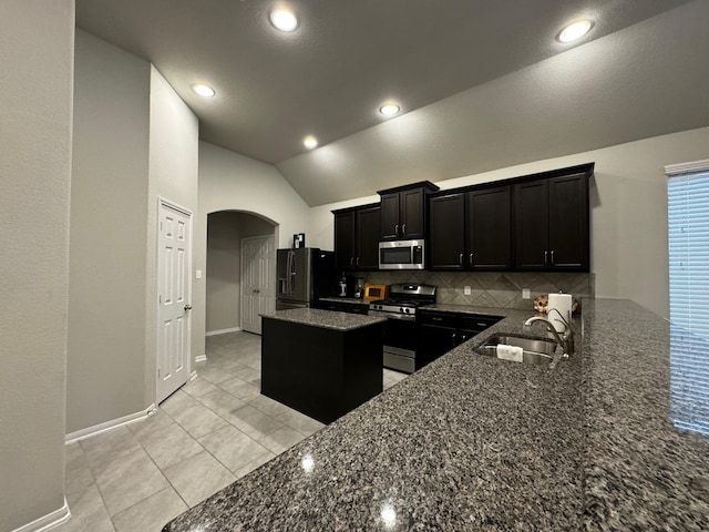 kitchen featuring appliances with stainless steel finishes, kitchen peninsula, light tile patterned floors, decorative backsplash, and lofted ceiling