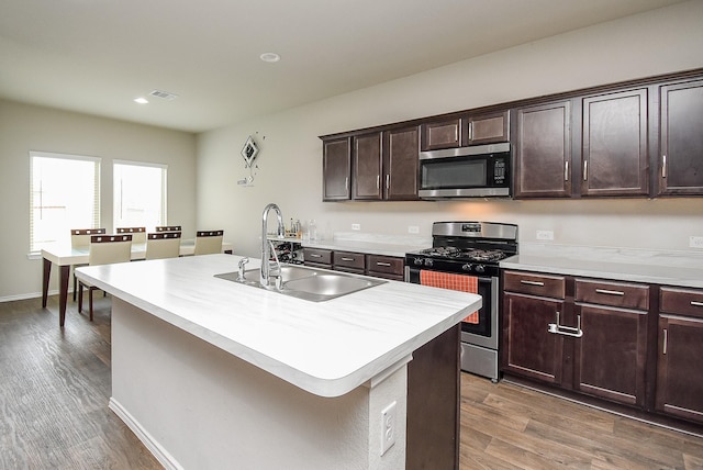 kitchen featuring dark brown cabinetry, sink, stainless steel appliances, dark hardwood / wood-style floors, and a kitchen island with sink