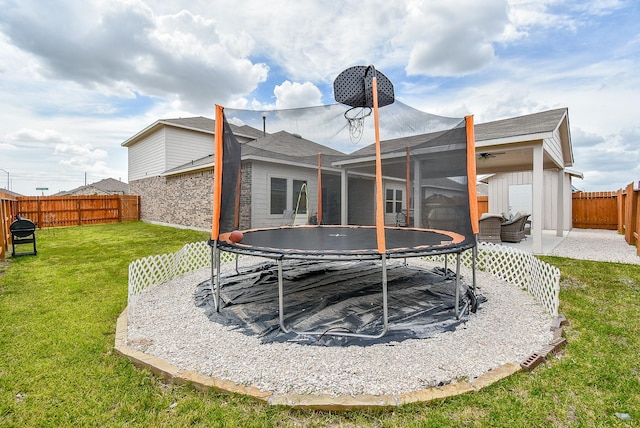 back of property with a yard, a storage unit, and a trampoline