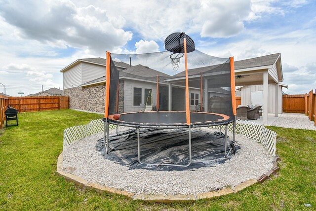 back of property with a yard, a storage unit, and a trampoline