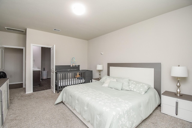 bedroom featuring ensuite bathroom and light colored carpet