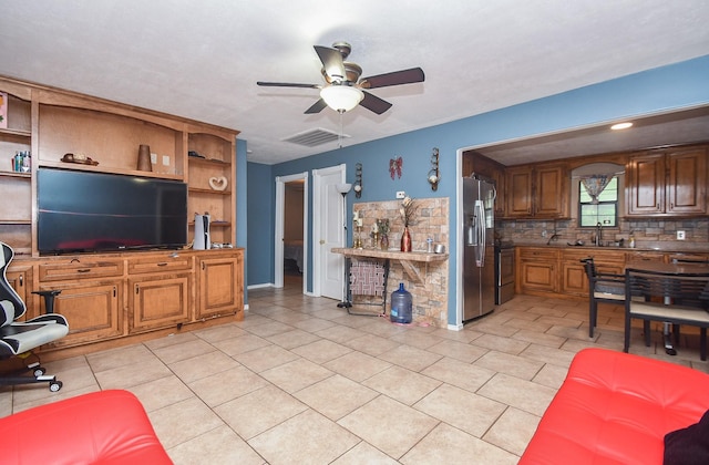 kitchen featuring stainless steel fridge, backsplash, black range oven, ceiling fan, and sink