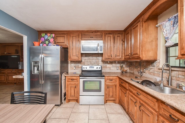 kitchen with sink, decorative backsplash, light tile patterned floors, light stone counters, and stainless steel appliances