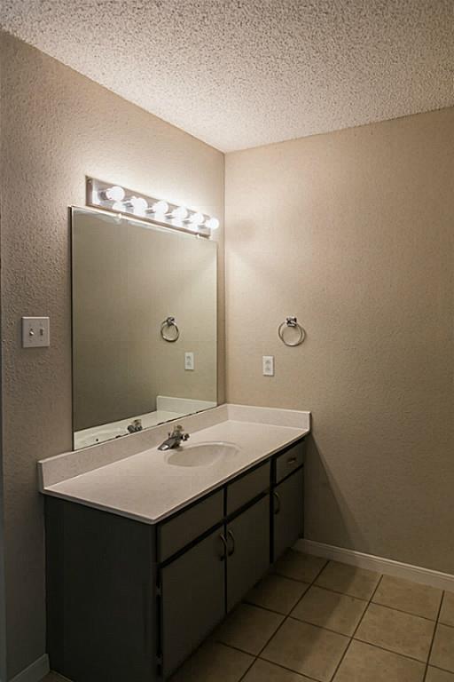 bathroom with vanity, a textured ceiling, and tile patterned flooring