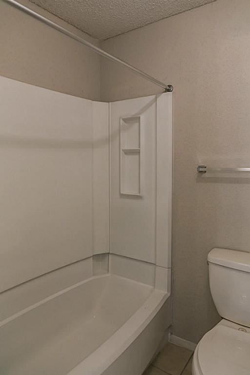 bathroom with shower / bathtub combination, tile patterned floors, a textured ceiling, and toilet