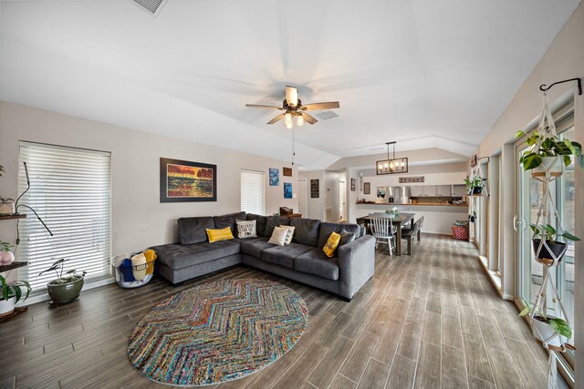 living room featuring ceiling fan with notable chandelier, vaulted ceiling, and hardwood / wood-style floors