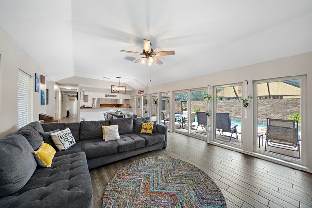 living room with ceiling fan with notable chandelier, dark hardwood / wood-style flooring, and lofted ceiling