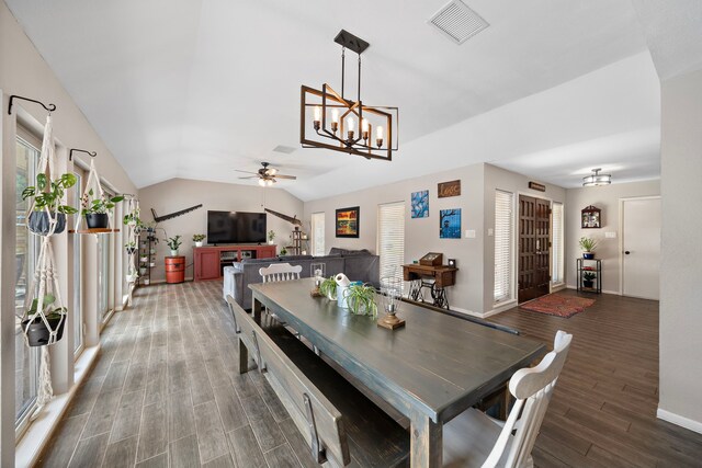 dining space with ceiling fan with notable chandelier, lofted ceiling, and dark wood-type flooring