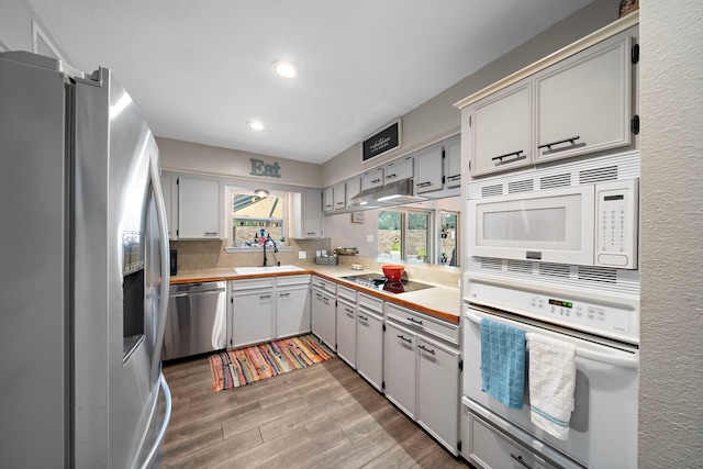 kitchen with decorative backsplash, stainless steel appliances, light wood-type flooring, and sink