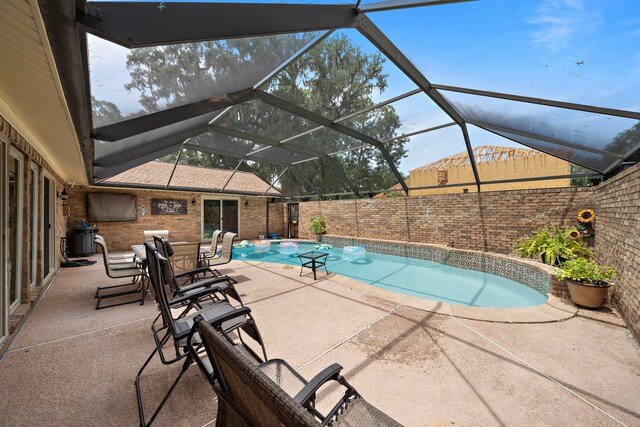 view of swimming pool featuring glass enclosure and a patio area