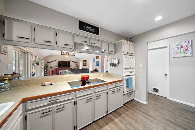 kitchen featuring lofted ceiling, white appliances, white cabinets, hardwood / wood-style flooring, and sink