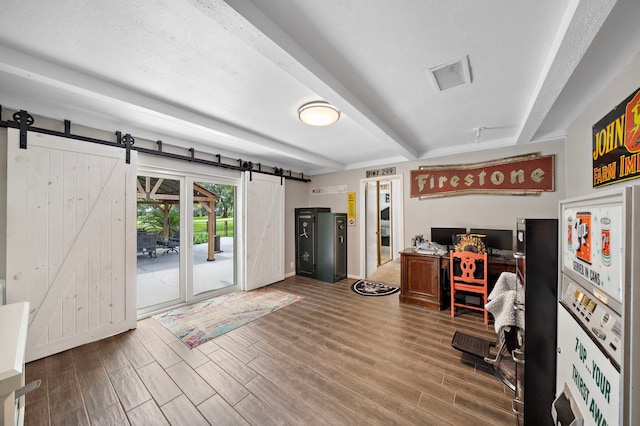 living room with a textured ceiling, a barn door, beam ceiling, and hardwood / wood-style flooring