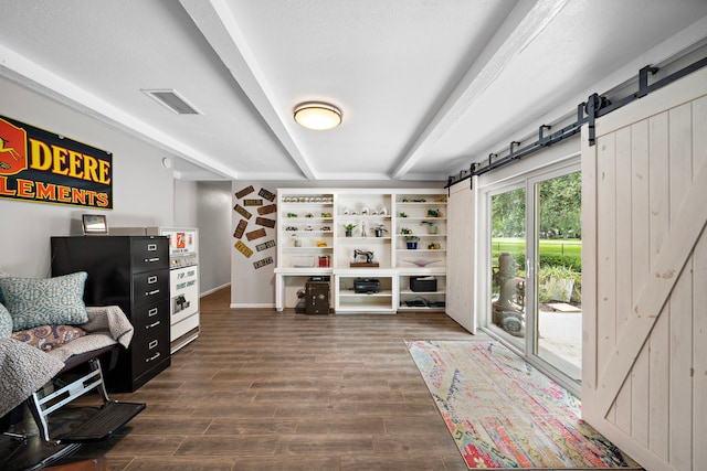 sitting room featuring beamed ceiling, a barn door, wood-type flooring, and a textured ceiling