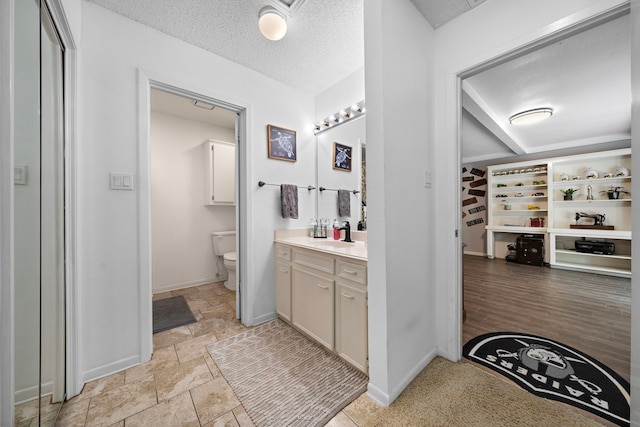 bathroom featuring tile patterned flooring, toilet, vanity, and a textured ceiling