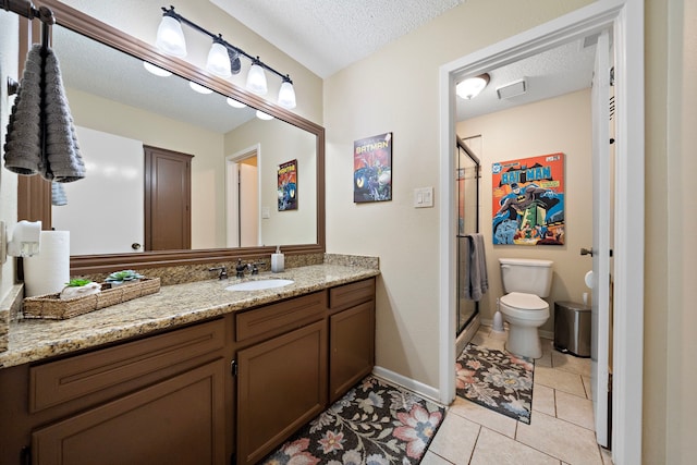 bathroom with tile patterned floors, toilet, vanity, and a textured ceiling