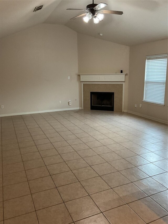 unfurnished living room with a tile fireplace, visible vents, baseboards, vaulted ceiling, and a ceiling fan