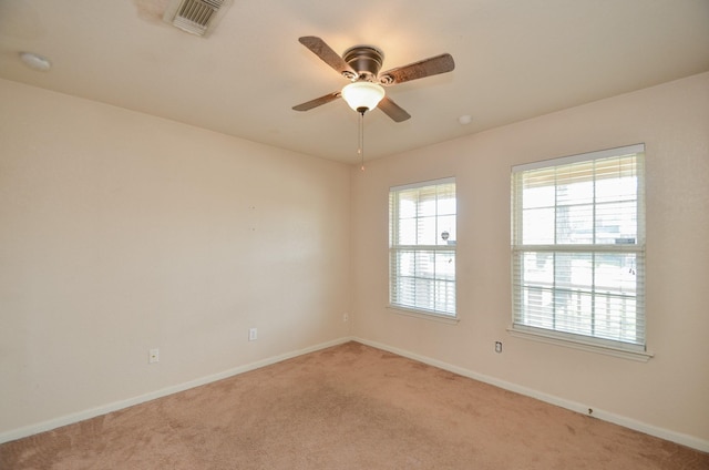 spare room with baseboards, a ceiling fan, visible vents, and light colored carpet