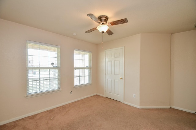 spare room with light carpet, ceiling fan, and baseboards