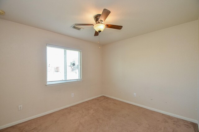 spare room with light carpet, visible vents, baseboards, and a ceiling fan