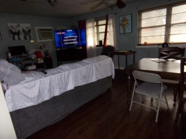 bedroom featuring ceiling fan, dark wood-type flooring, a wall mounted air conditioner, and multiple windows