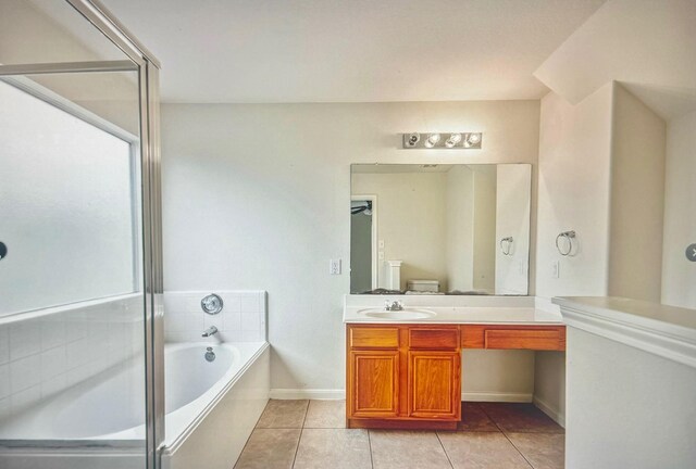 bathroom featuring a relaxing tiled tub, vanity, and tile patterned floors