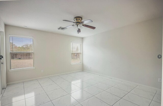 spare room featuring baseboards, plenty of natural light, visible vents, and a ceiling fan