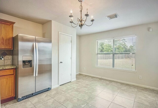 kitchen featuring visible vents, brown cabinetry, baseboards, stainless steel fridge with ice dispenser, and pendant lighting