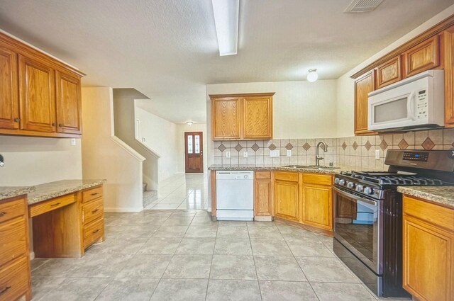 kitchen featuring brown cabinetry, white appliances, a sink, and light stone counters