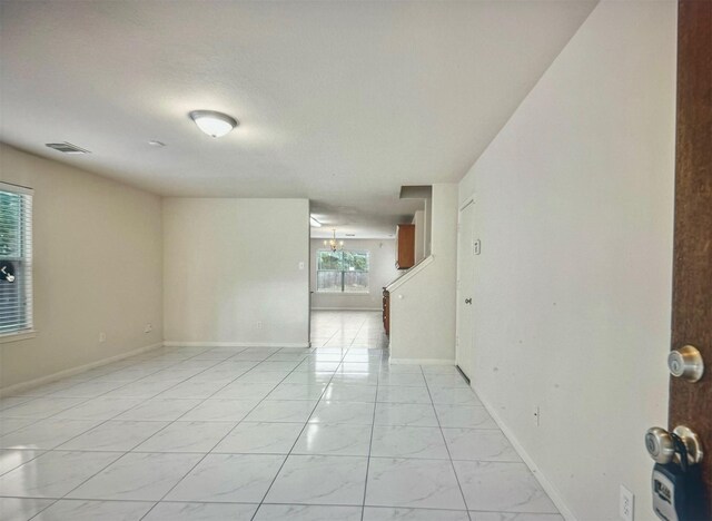 empty room with marble finish floor, visible vents, and baseboards