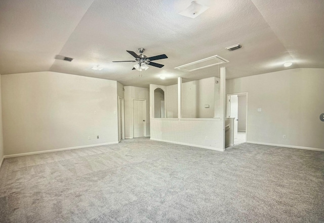 empty room with attic access, lofted ceiling, visible vents, and carpet floors