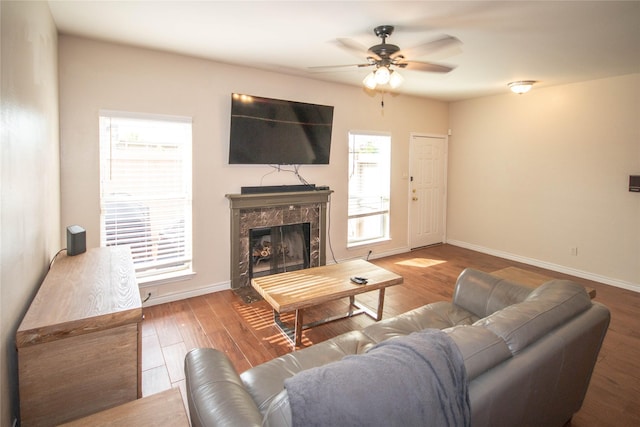 living room with hardwood / wood-style flooring, ceiling fan, and a premium fireplace