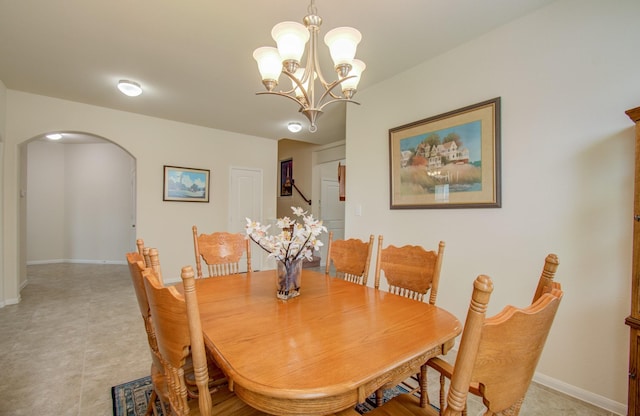 dining room featuring arched walkways, baseboards, and a notable chandelier