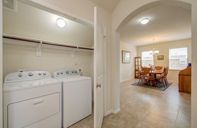 laundry room featuring laundry area, washing machine and dryer, light tile patterned flooring, arched walkways, and a notable chandelier