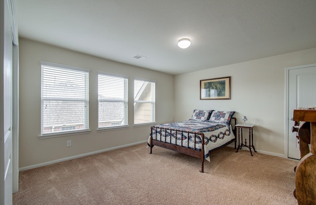 bedroom featuring baseboards, visible vents, and light colored carpet