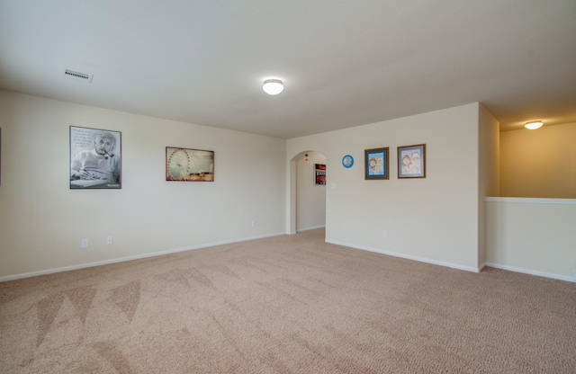 carpeted spare room featuring arched walkways, baseboards, and visible vents