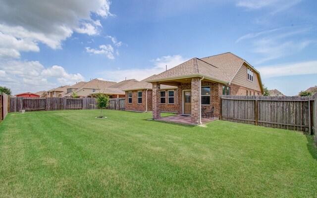back of house featuring brick siding, a fenced backyard, a lawn, and a patio area