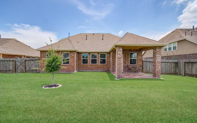 back of property with roof with shingles, brick siding, a fenced backyard, a patio area, and a lawn
