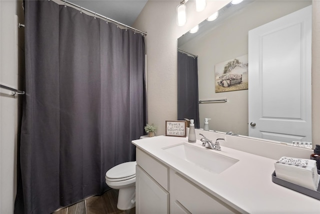 bathroom with toilet, vanity, and wood-type flooring