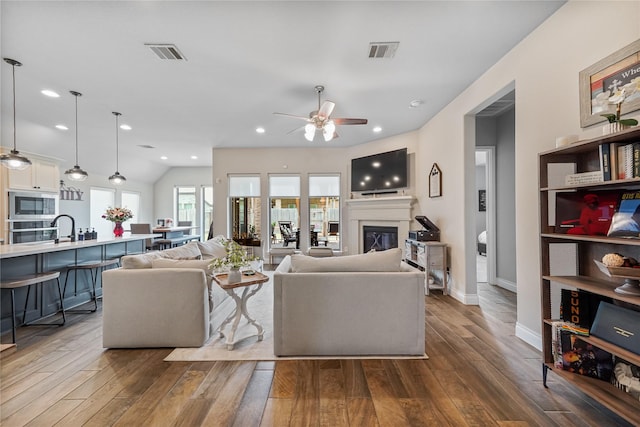 living room featuring ceiling fan, vaulted ceiling, sink, and hardwood / wood-style flooring